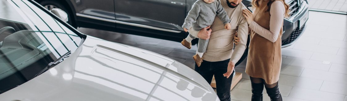 Family with toddler girl choosing a car in a car showroom